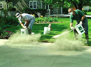 Concrete contractors throwing color hardener on a fresh concrete slab.