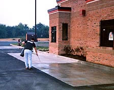 Densifiers work on new and old concrete, here a man is applying densifier with a hand held pump sprayer to a restaurant drive-thru window area.