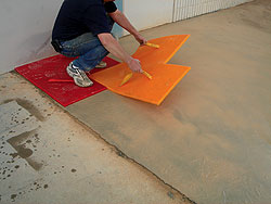 Provided the wall of the building and any adjoining slab are perpendicular to one another, and you are using a square-pattern stamping tool such as the 36-inch Ashlar Slate shown here, begin with the edges of the stamp aligned to a corner of the area you are stamping.