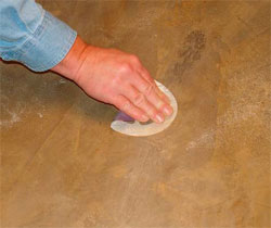 As the material cures, the repair is blended into the surrounding concrete with sandpaper.